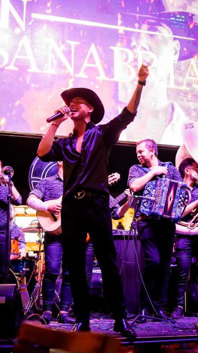 Ryan Sanabria en tarima con su banda bajo luces moradas